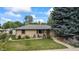 Single story brick home with a well-manicured lawn and flourishing garden at 1217 Lincoln St, Longmont, CO 80501