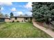 Charming single-story home featuring a well-manicured front yard, mature trees, and inviting curb appeal at 1217 Lincoln St, Longmont, CO 80501