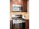 Modern kitchen with stainless steel microwave and range, complemented by granite counters and dark wood cabinets at 3402 N Clayton St, Denver, CO 80205