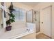 Modern bathroom featuring a shower, soaking tub, window, and a view of the landscaped surroundings at 12 Apache Plume St, Brighton, CO 80601