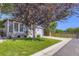 Single-Gathering home with a manicured lawn, tree, and driveway leading to the garage at 12 Apache Plume St, Brighton, CO 80601