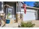 Inviting front porch showcasing stone accents, hanging flower baskets, and an American flag at 12 Apache Plume St, Brighton, CO 80601