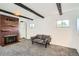 Cozy living room with a brick fireplace, exposed wood beams, and a large window providing natural light at 2692 S Osceola St, Denver, CO 80219