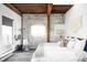 Stylish bedroom features exposed brick, wooden beams, large window, and minimalist decor at 3733 N Franklin St, Denver, CO 80205