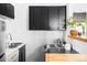 Compact kitchen with black cabinets, stainless steel appliances, and a pass-through to the living area at 3733 N Franklin St, Denver, CO 80205