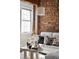 Bright living space with exposed brick, large window, white sofa with decorative pillows, and modern coffee table at 3733 N Franklin St, Denver, CO 80205