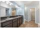Bathroom with granite countertops, double sinks, shower, and walk-in closet access at 1694 Jennifer St, Brighton, CO 80601