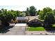 An aerial view of a stone house with solar panels, mature trees, and a well-kept lawn at 8644 S Brentwood St, Littleton, CO 80128