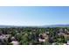 Aerial view showing a neighborhood with lush green trees and mountains and a lake in the distance at 8644 S Brentwood St, Littleton, CO 80128