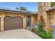 Close-up of a stone house with a brown garage door, solar panels, and red roses climbing near the entrance at 8644 S Brentwood St, Littleton, CO 80128