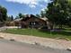 Stone-clad house featuring an A-frame roof, front deck, well-maintained lawn, solar panels, and chain-link fence at 8644 S Brentwood St, Littleton, CO 80128