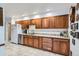 Well-lit kitchen featuring wood cabinets, granite countertops, stainless steel appliances, and neutral tile flooring at 8644 S Brentwood St, Littleton, CO 80128