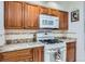 Kitchen featuring wood cabinetry, white appliances, granite countertops, and tile backsplash at 8644 S Brentwood St, Littleton, CO 80128
