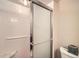 Bathroom featuring a clear glass shower door, white tiles, grab bar and toilet at 4570 E Yale Ave # 606, Denver, CO 80222