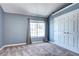 Cozy bedroom with neutral walls, plush carpet, a bright window, and closet with mirrored doors at 1907 S Balsam St, Lakewood, CO 80227