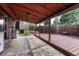 Back patio featuring a covered wood deck, concrete slab, and access to a fenced backyard with flower beds at 7425 S Dexter St, Centennial, CO 80122