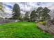 Lush green backyard with mature trees, surrounded by a wood fence at 7425 S Dexter St, Centennial, CO 80122