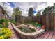 Brick-lined flower bed with lush plants and flowers adjacent to a wood deck and fenced backyard at 7425 S Dexter St, Centennial, CO 80122