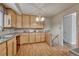 Functional kitchen with ample wooden cabinets, tile backsplash, laminate flooring, and easy access to basement at 7425 S Dexter St, Centennial, CO 80122
