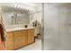 Bright bathroom featuring wood cabinets, a large mirror, a shower, and tiled flooring at 18399 Wagon Trl, Mead, CO 80542