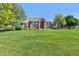 Well-maintained brick home with a manicured lawn and mature trees on a sunny day at 18399 Wagon Trl, Mead, CO 80542
