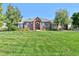 Well-maintained brick home with a manicured lawn and mature trees on a sunny day at 18399 Wagon Trl, Mead, CO 80542