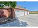Red brick home featuring a 3 car garage with white doors and long driveway at 18399 Wagon Trl, Mead, CO 80542