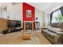 Comfortable living room features a fireplace with a red accent wall, large window, and cozy sofa at 693 Delwood Ct, Highlands Ranch, CO 80126