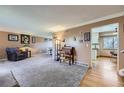 Cozy living room featuring plush carpeting, a comfortable armchair, and adjacent dining area at 8210 Hoyt Ct, Arvada, CO 80005