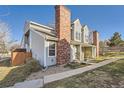 View of the townhome showing walkway, brick chimney, gray siding, and fenced-in yard at 8391 W 90Th Pl, Westminster, CO 80021