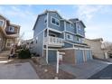 Three-story blue home featuring an attached garage and a charming second-story balcony at 10470 W 83Rd Ave, Arvada, CO 80005
