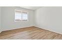 Bright bedroom with laminate flooring, white walls, and a large window at 4495 Boone Cir, Brighton, CO 80601