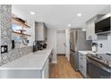 Modern kitchen features stainless steel appliances, grey cabinetry, quartz countertops, and decorative backsplash at 10810 W Alamo Pl, Littleton, CO 80127