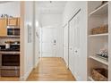 Bright hallway with hardwood floors, white walls, closet doors, and view of the kitchen area at 444 17Th St # 208, Denver, CO 80202