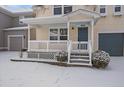 Front porch with white railings and snowy landscaping at 9442 E 106Th Dr, Commerce City, CO 80640