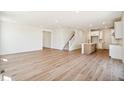 Bright, open-concept living room features wood floors, staircase, and view to the modern kitchen at 6207 E 155Th Pl, Brighton, CO 80602