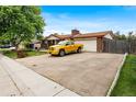 Wide driveway leading to a ranch-style home and garage, with a yellow truck parked at 6336 W 71St Pl, Arvada, CO 80003