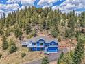 Aerial view showcases this blue home with a deck, nestled among towering trees, with a driveway at 33633 Elk Run, Evergreen, CO 80439
