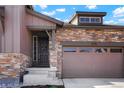 Inviting exterior with a stylish front door, stone accents, manicured landscaping and an attached two-car garage at 8052 Mount Kataka St, Littleton, CO 80125