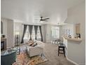 Bright living room boasts a ceiling fan, fireplace, a large window with stylish curtains, and an open floor plan at 5726 N Genoa Way # 201, Aurora, CO 80019