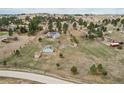 Wide aerial view of a home on a sprawling lot with a barn, shed, and lush surrounding landscape at 1233 Starling Ln, Elizabeth, CO 80107