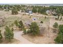 Scenic aerial view of a rural property with a gray home, surrounded by lush trees and open land at 1233 Starling Ln, Elizabeth, CO 80107