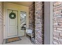 Inviting entryway with a decorative wreath on the front door and a cozy bench accented by a textured stone wall at 10401 Maplebrook Way, Highlands Ranch, CO 80126