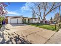 Wide view of a home with a large front lawn, driveway and detached garage at 135 Garnet St, Broomfield, CO 80020