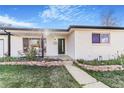 Close-up view of home's white brick facade, covered porch and newly landscaped yard at 135 Garnet St, Broomfield, CO 80020