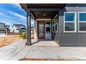 Inviting front porch with a stylish wood door, gray siding, and stone accents at 5773 N Jericho Way, Aurora, CO 80019