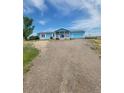 Inviting single-story home with covered front porch and attached two car garage, surrounded by a gravel yard at 58117 E 42Nd Dr, Strasburg, CO 80136