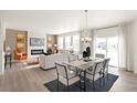 Open-concept dining room with modern lighting, large windows, and access to living area at 13802 Quartz St, Mead, CO 80504