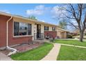 A close-up of a charming home featuring a brick exterior and walkway to the front door at 2792 S Stuart St, Denver, CO 80236