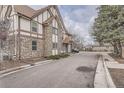 A side angle of a beautiful Tudor-style townhouse with a stone facade and well-kept landscaping at 17936 Becket Dr, Parker, CO 80134